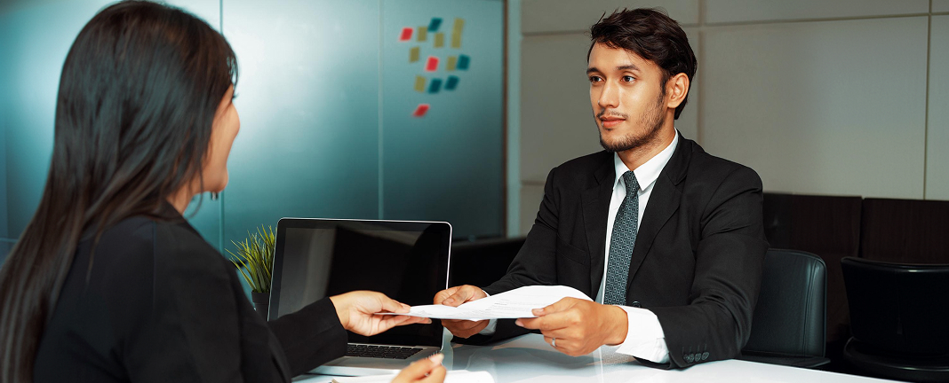 Recruiter handing placement documents to a student during an interview
